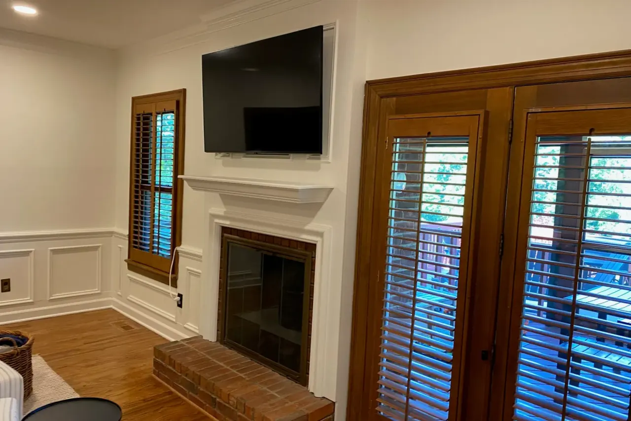 Living room with painted wainscoting and crown molding around a fireplace and French doors, one of our interior painting projects for Bellevue homes