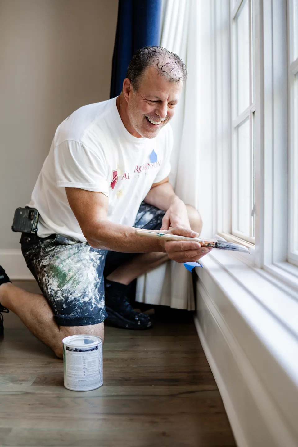 Alan Robinson brushing paint onto window trim in a Nashville home